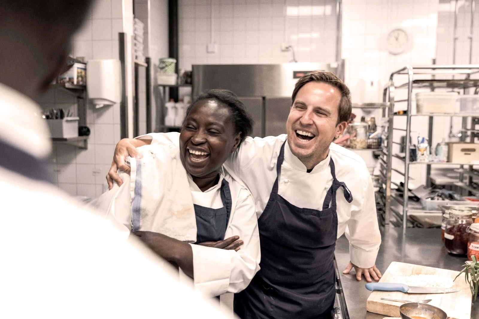 Two chefs laughing together in a restaurant kitchen