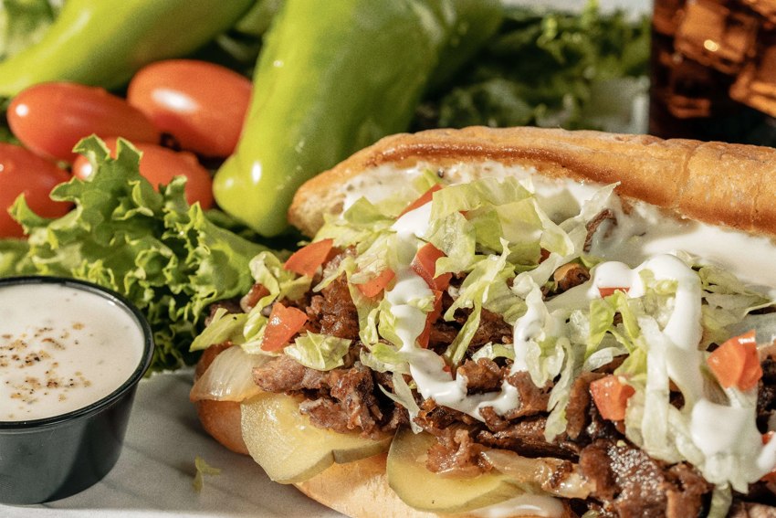 Cheesesteak sandwich topped with cheese and vegetables
